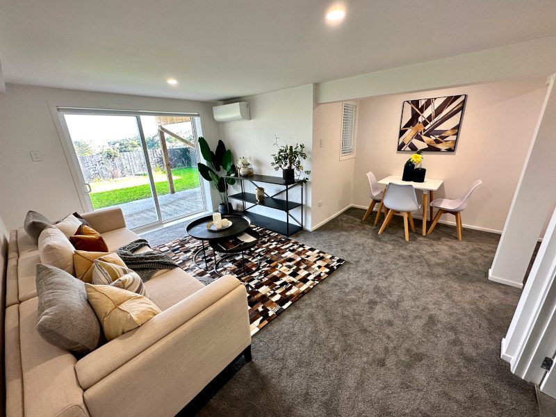 Basement renovation after: Modern living room with sofa, rug, table, chairs, and stylish decor. Bright and airy space.