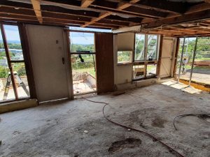 Basement renovation before: Exposed ceiling, bare concrete floor, and open doorways during home remodel project.
