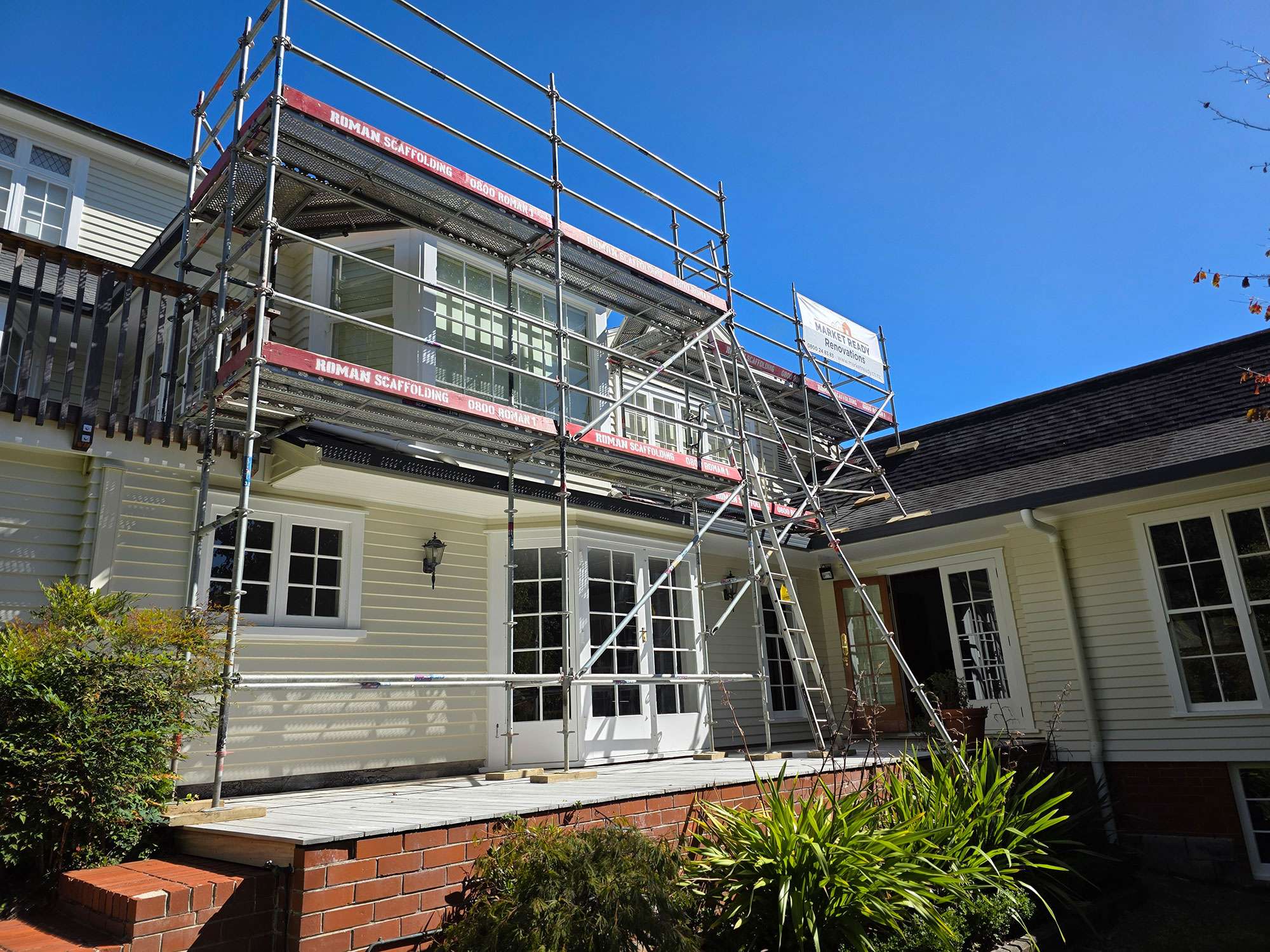 Window rot repair case study: House with scaffolding for window renovation and restoration project against a blue sky.