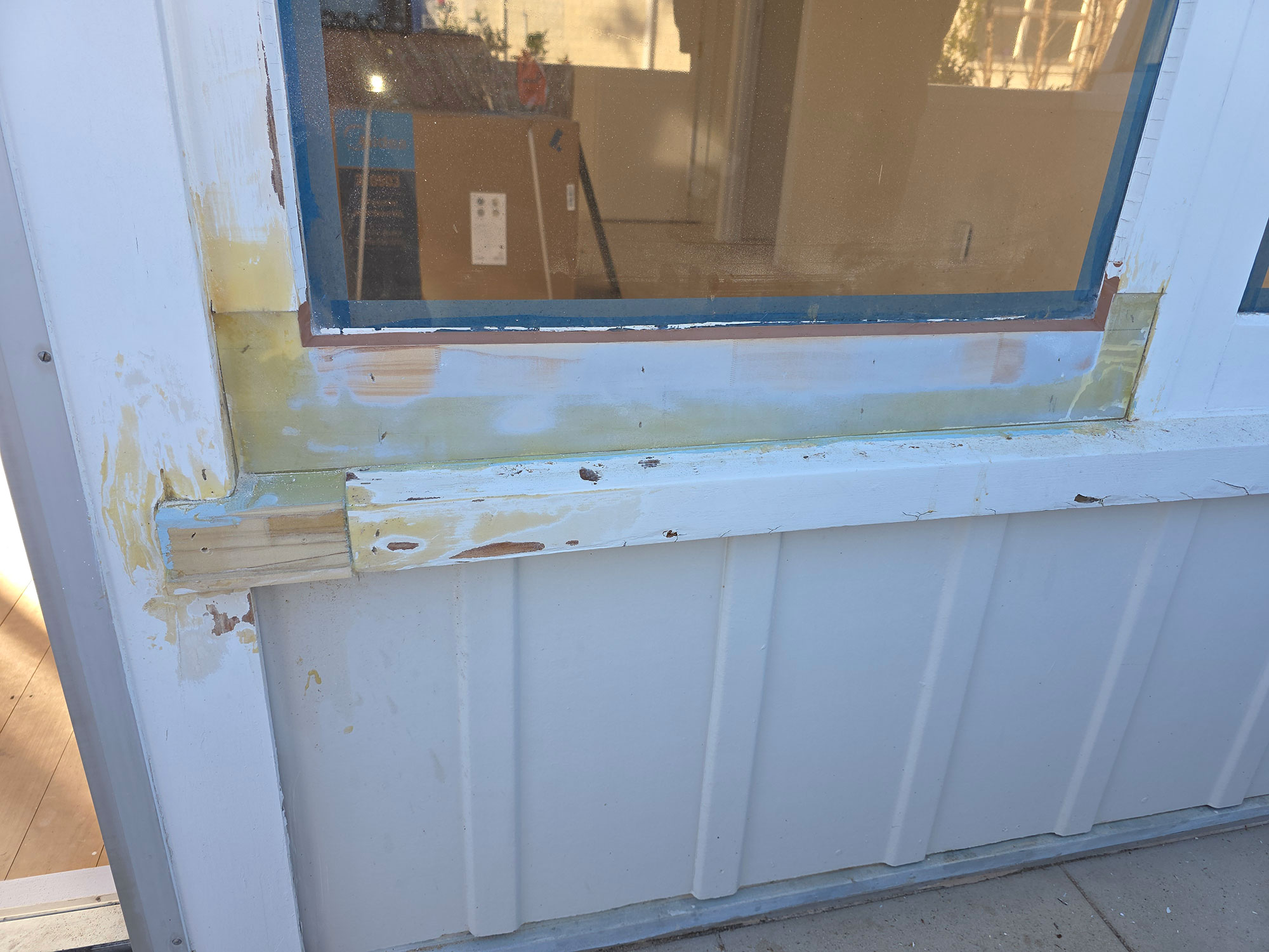 Window rot repair case study: Close-up of damaged, rotting window frame being restored. White paint, wood repair, window refurbishment.
