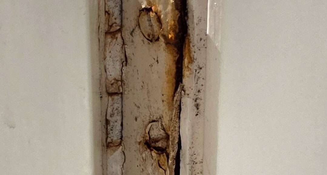 Close-up of severe window rot with cracked paint and exposed wood, showcasing damage from moisture and decay. Window rot case study.