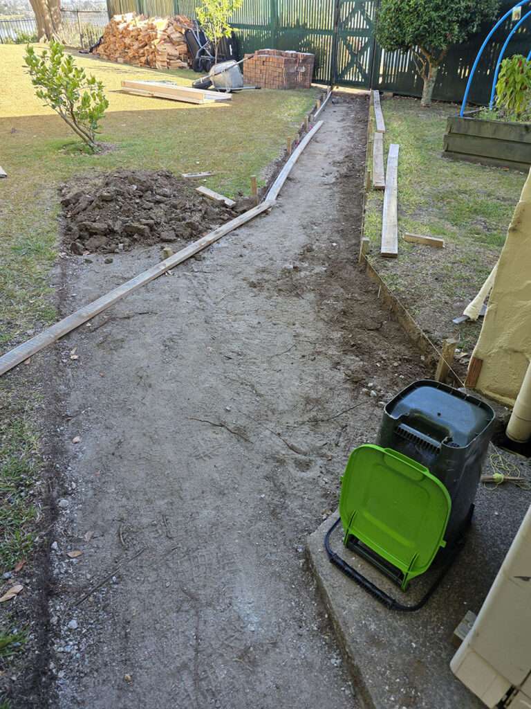 Building a brick path. Garden pathway under construction with wooden border and bricks. DIY landscaping project.