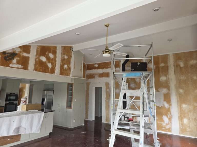 Interior painting and flooring project, showing a ladder, unpainted walls, new kitchen cabinets and preparations.