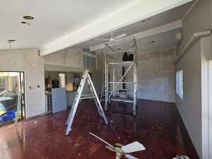 Interior renovation with metal scaffolding, ladder, and Lemonade color flooring. Home remodeling project in progress.