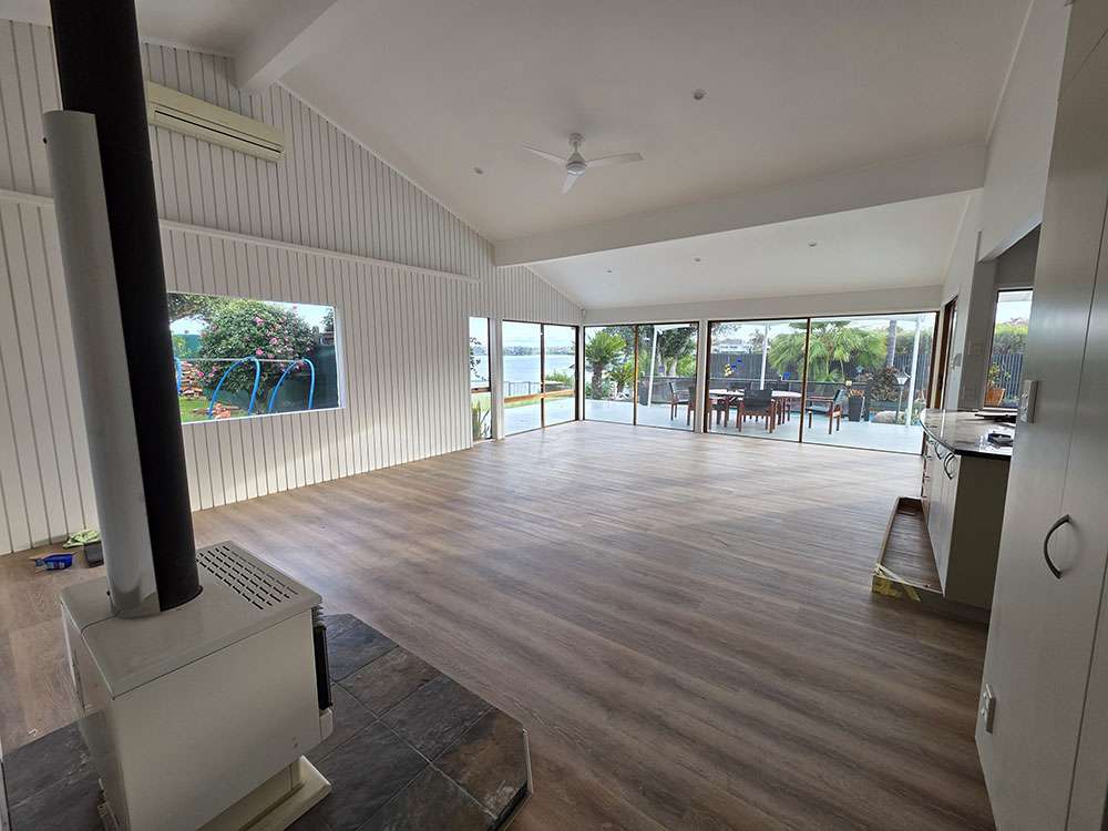 Spacious living room showcasing new Lemonade wood flooring, bright interior, and panoramic views of the outdoors.