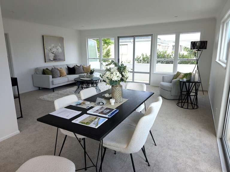 Bright living room with gray carpet, modern furniture, black dining table, white chairs, and natural light. Interior design.