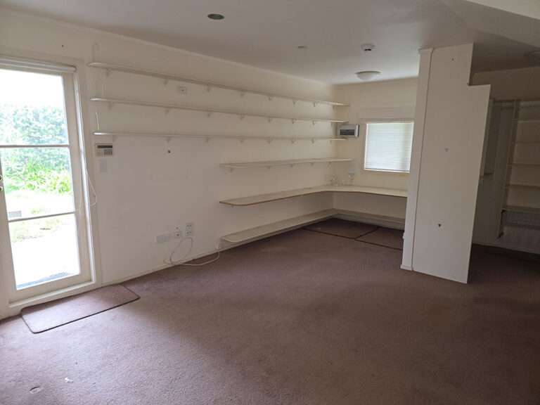 Interior view of empty room with shelves, window, and door for home renovation or remodeling project.