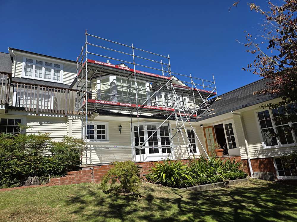 Scaffolding system on a house for construction or repair work. Exterior view, clear blue sky. Scaffolding case study.
