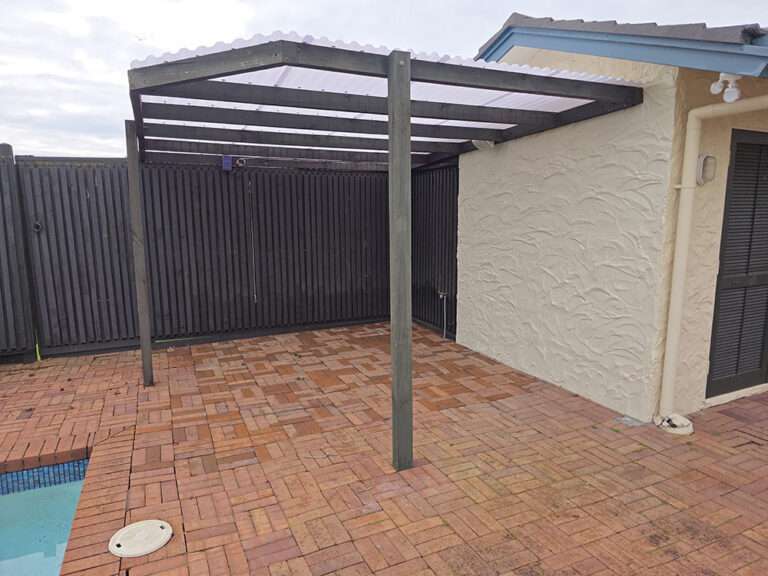 Outdoor patio with brick pavers, dark wood pergola, and privacy fence. Spa removal and re-bricking project.