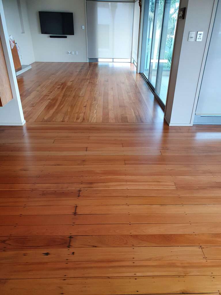 Refreshed timber floor in a bright living room. Polished hardwood flooring after timber floor refresh, showcasing natural wood grain.