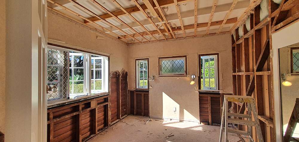 Interior wall insulation project: Room with exposed studs and ceiling joists, showcasing the process of insulating interior walls.