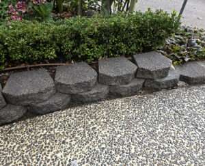Paving clean-up case study: Stone retaining wall and pebble paving cleaned and restored, showcasing effective paving clean-up.