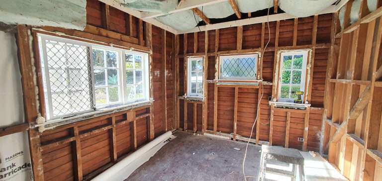 Interior wall insulation project: Exposed wall studs and windows ready for insulation, improving energy efficiency.