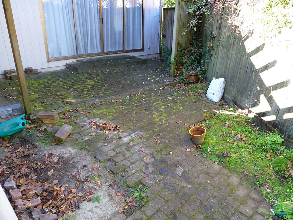 Dirty brick paving before clean-up. Moss, leaves, and grime cover the patio. Paving clean-up case study.
