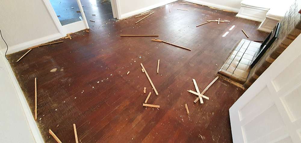 Timber floor refresh case study showing damaged hardwood floor with wood debris before restoration.
