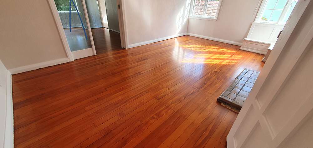 Refreshed timber floor in a bright room. Case study showing a timber floor refresh with a lustrous finish. Wooden flooring.