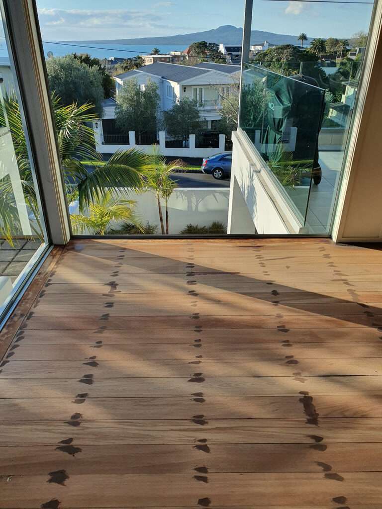 Refreshed timber floor with a view of the city and ocean, showcasing the results of a timber floor refresh project.