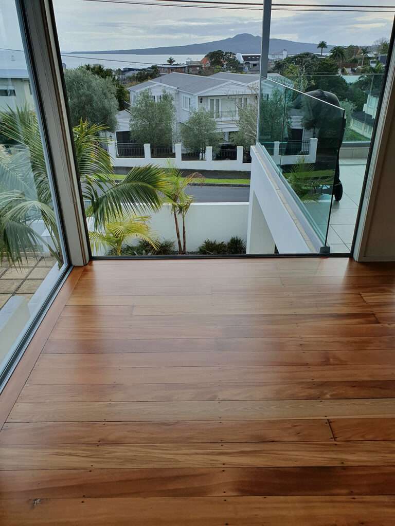 Refreshed timber floor in a modern home with a view of the landscape. Case study of timber floor refresh.