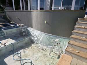 Market Ready past project: Concrete pool renovation with new gray concrete wall and pool area preparation. Exterior view.