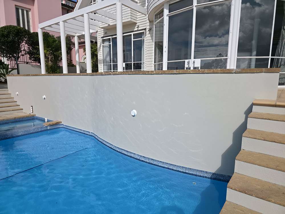 Exterior concrete wall near a pool in a Market Ready past project, showcasing architectural design and landscaping.