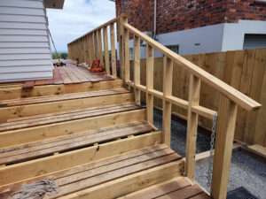 Wooden decking handrail construction. New deck stairs with safety railing installation, unfinished wood. Decking as handrail case study.