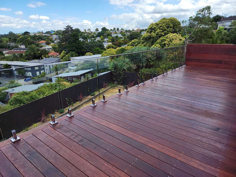 Decking handrail with glass panels, showcasing a modern outdoor deck design with a clear view of the landscape.