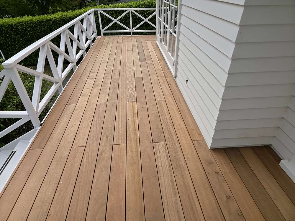Repaired Kwila decking with white railing and house siding, showcasing decking repair case study.