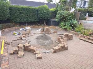 Brick releveling project in progress. Bricks stacked, sand pile, tools visible outdoor renovation.