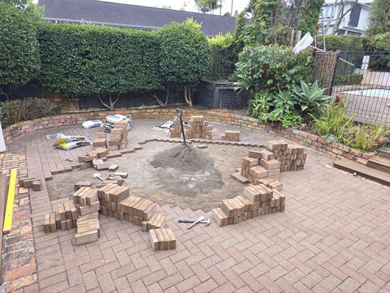 Brick releveling project in progress. Bricks stacked, sand pile, tools visible outdoor renovation.
