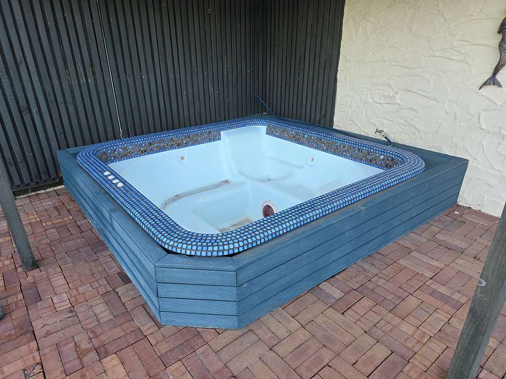 Brick Releveling: Outdoor hot tub with blue tile trim and brick patio. Illustrates brick patio repair and releveling.