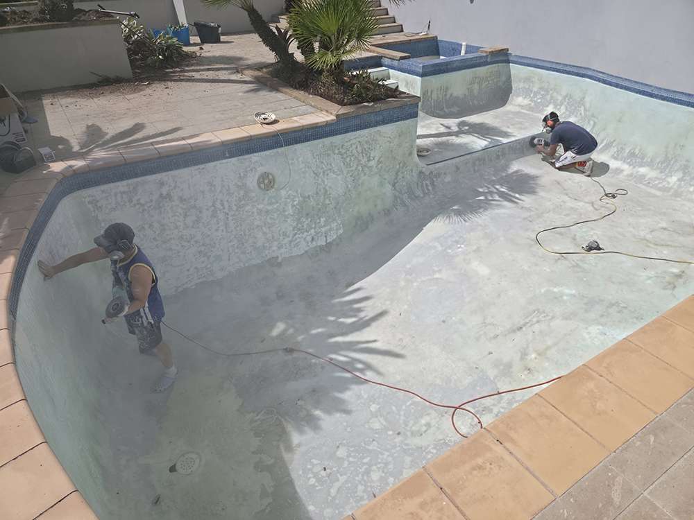 Pool painting and repair: Workers grinding the inside of an empty pool for resurfacing and pump repair. Case study.