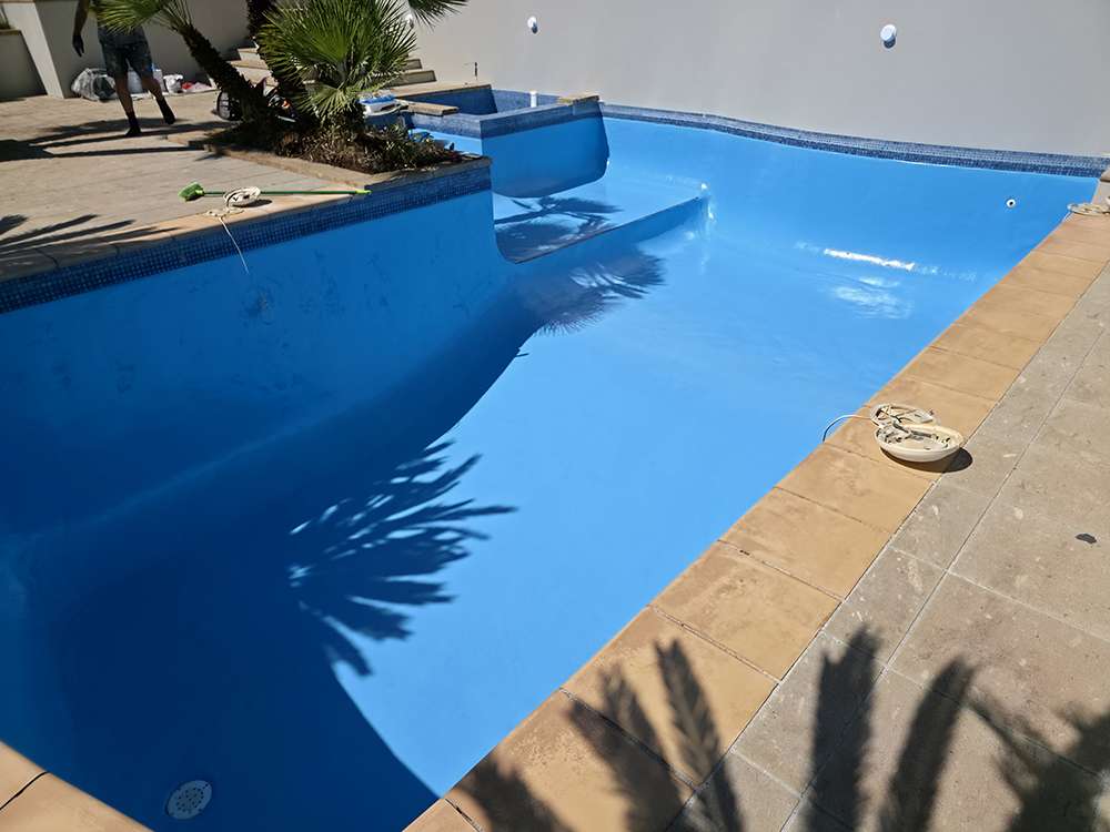 Freshly painted blue swimming pool, showcasing pool painting services. Clean, modern pool design with clear water.